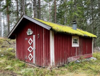 Det står Åsahytta og en speiderlilje på skiltet, men hytta ser lite brukt ut. Den ligger langs stien i skogen mellom Jaklefoss og Damtjern.